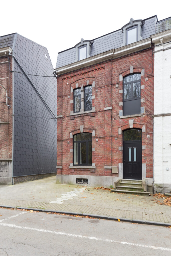 Façade à rue en brique et menuiseries noires de la maison de maître de Gembloux