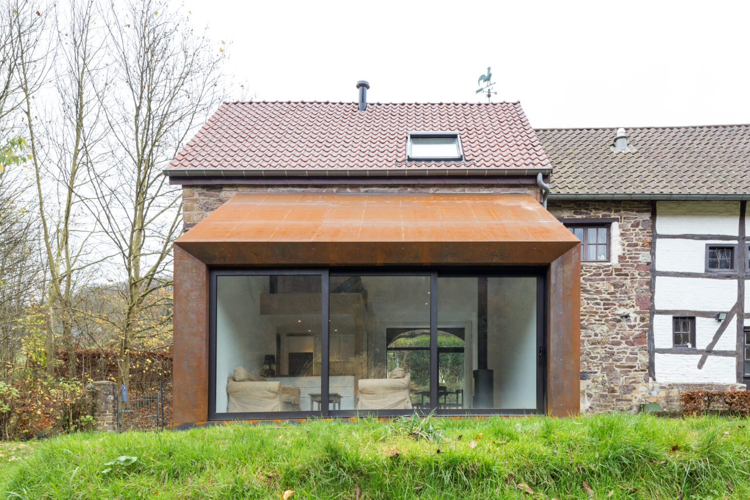 Extension corten et large baie vitrée greffées sur la grange à colombages de Lustin
