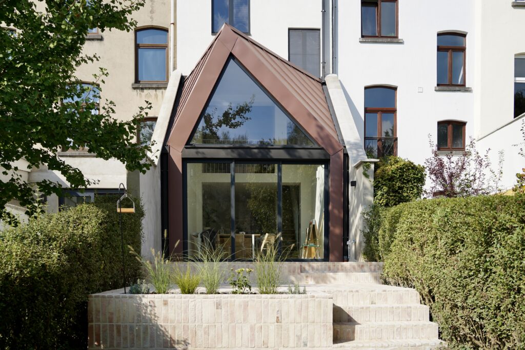 Extension en zinc rougeâtre et terrasse en pierre ouvrant le séjour sur le jardin, Auderghem