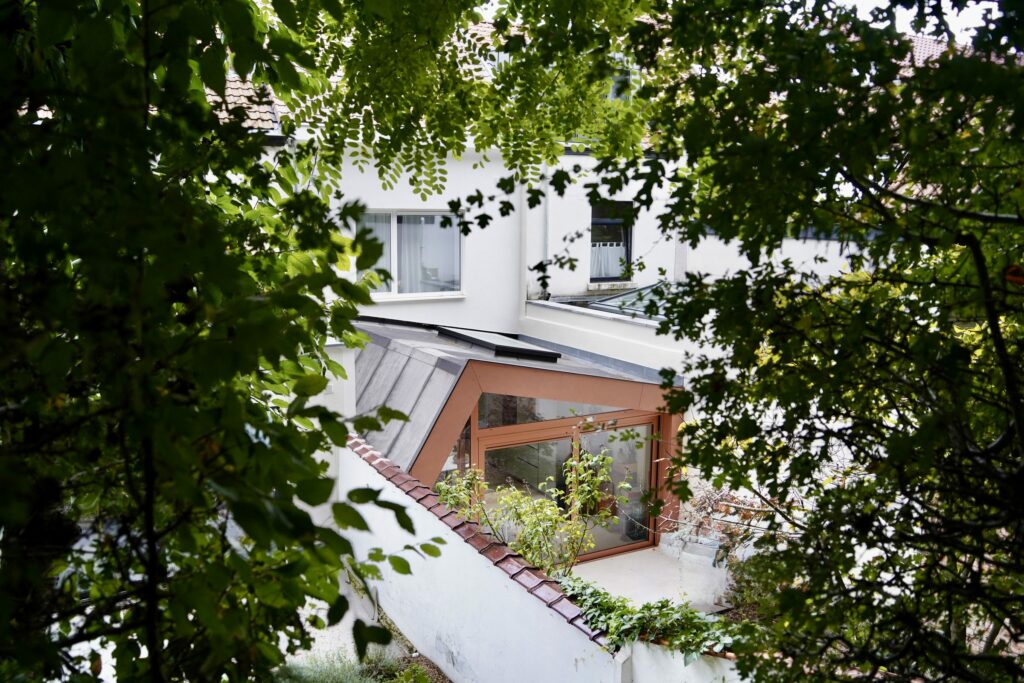 Extension terracotta vue depuis le haut du jardin à travers les arbres, maison à Auderghem