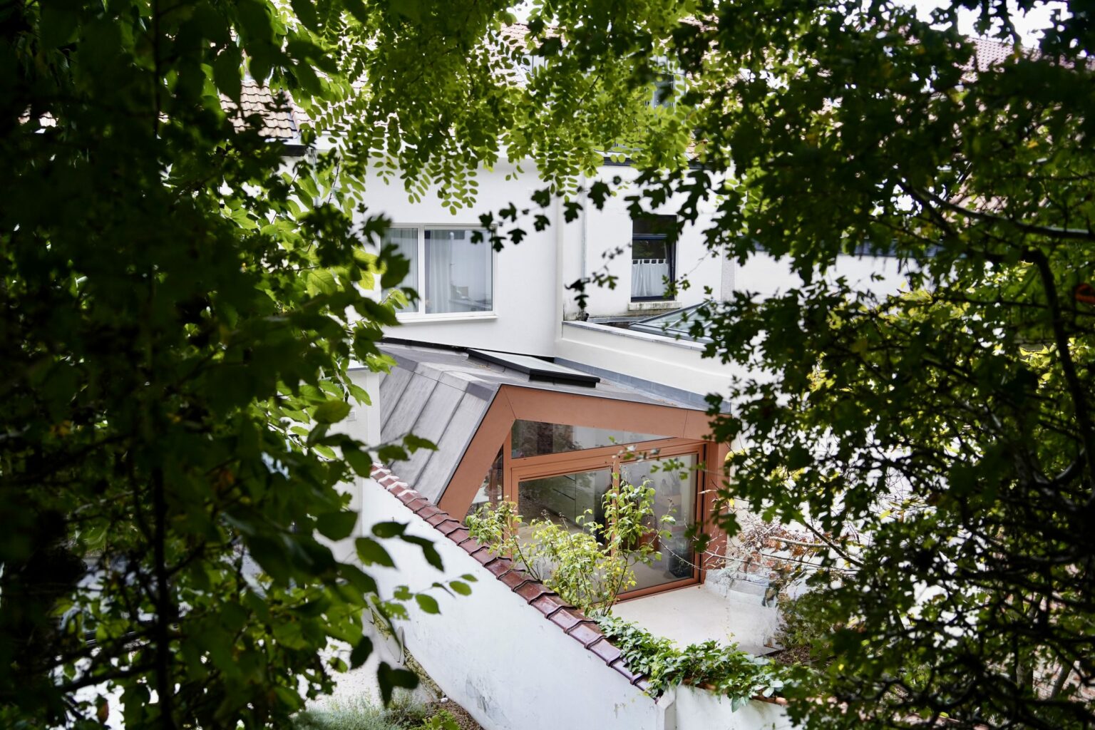 Extension terracotta vue depuis le haut du jardin à travers les arbres, maison à Auderghem