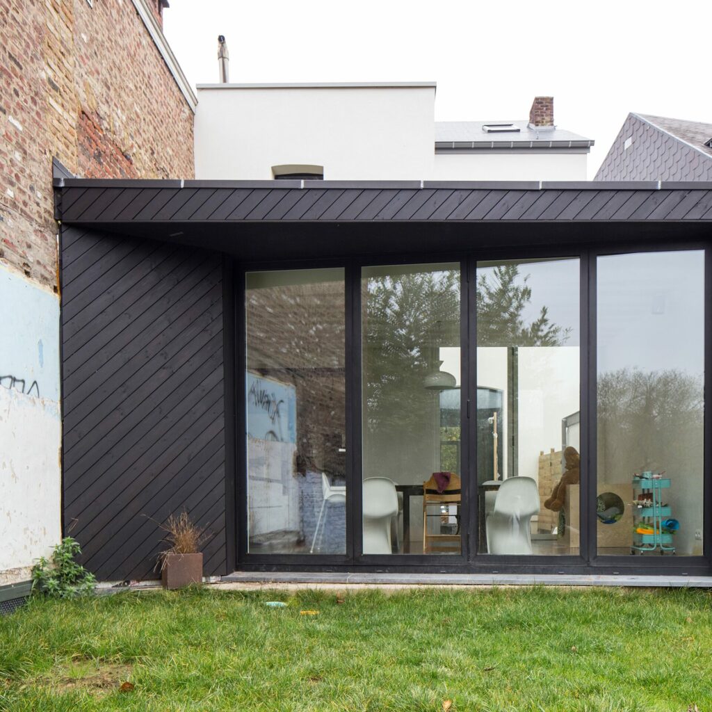 Extension contemporaine en bardage noir ouverte sur le jardin, maison de maître à Gembloux
