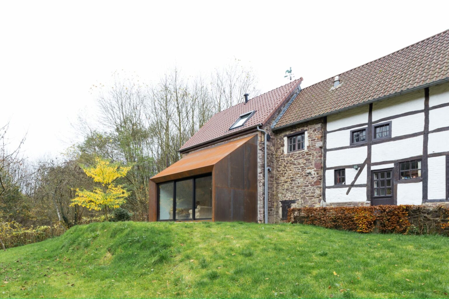 Grange du XVIIIe siècle rénovée à Lustin, façade à colombages et volume en acier corten côté jardin