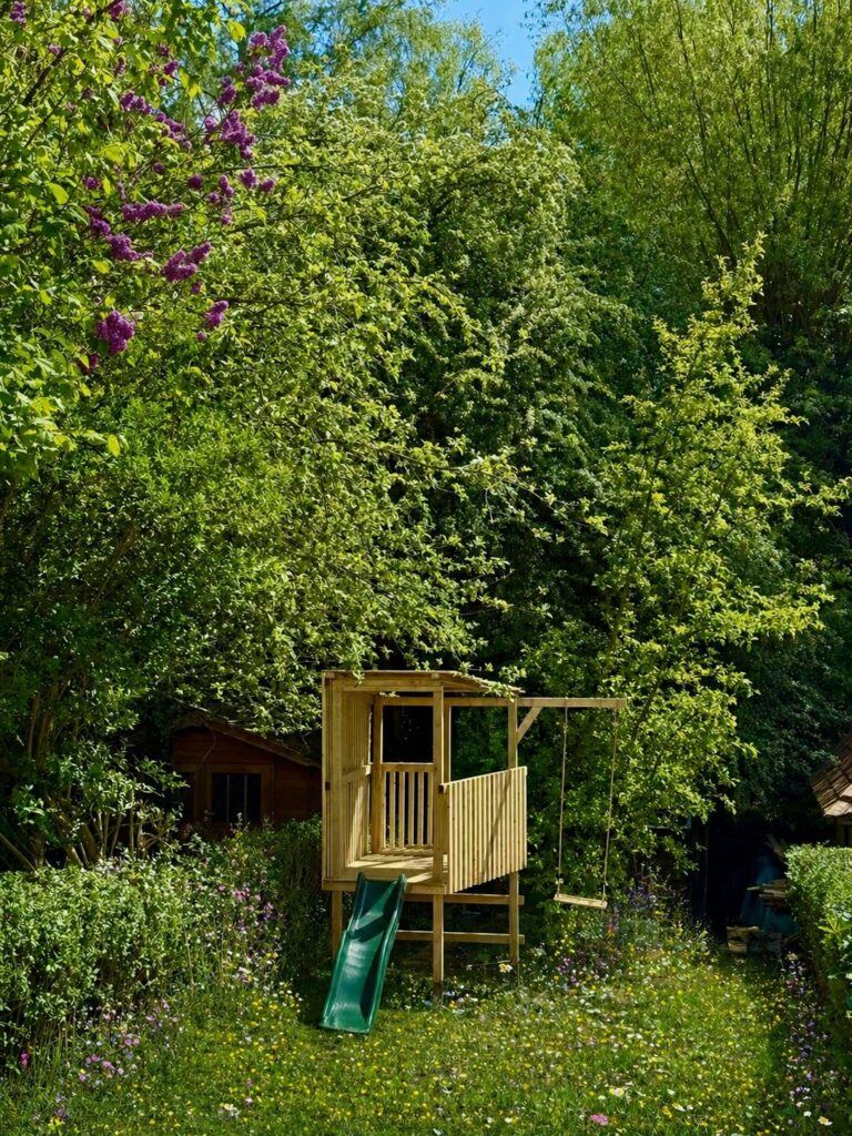 Cabane de jeux en bois sur pilotis avec toboggan et balançoire dans un jardin naturel, Auderghem