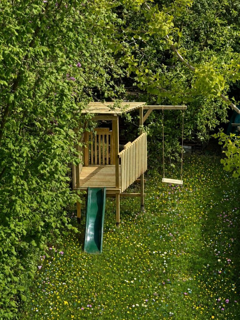 Cabane de jeux en bois sur pilotis avec toboggan dans le jardin d'une maison à Auderghem