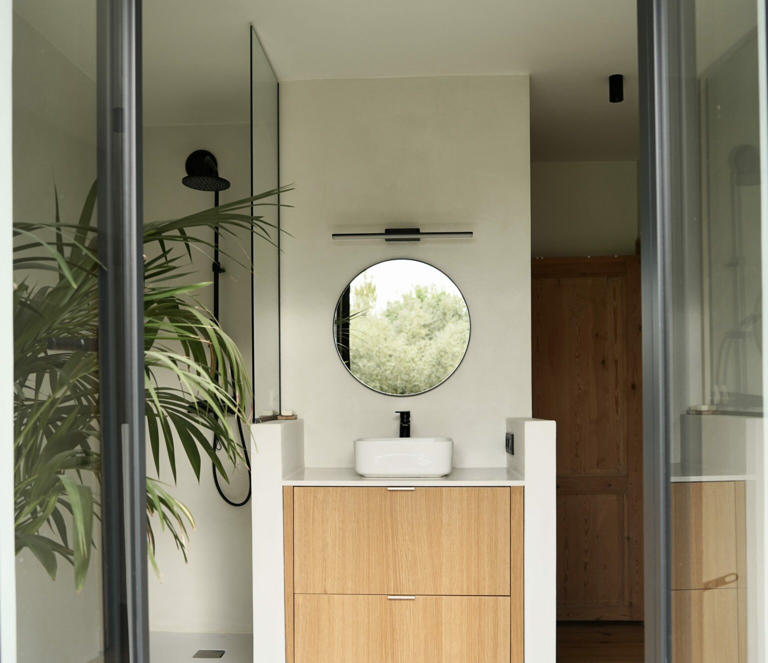 Salle de bains en chêne et enduit à la chaux avec miroir rond, rue de la Vignette