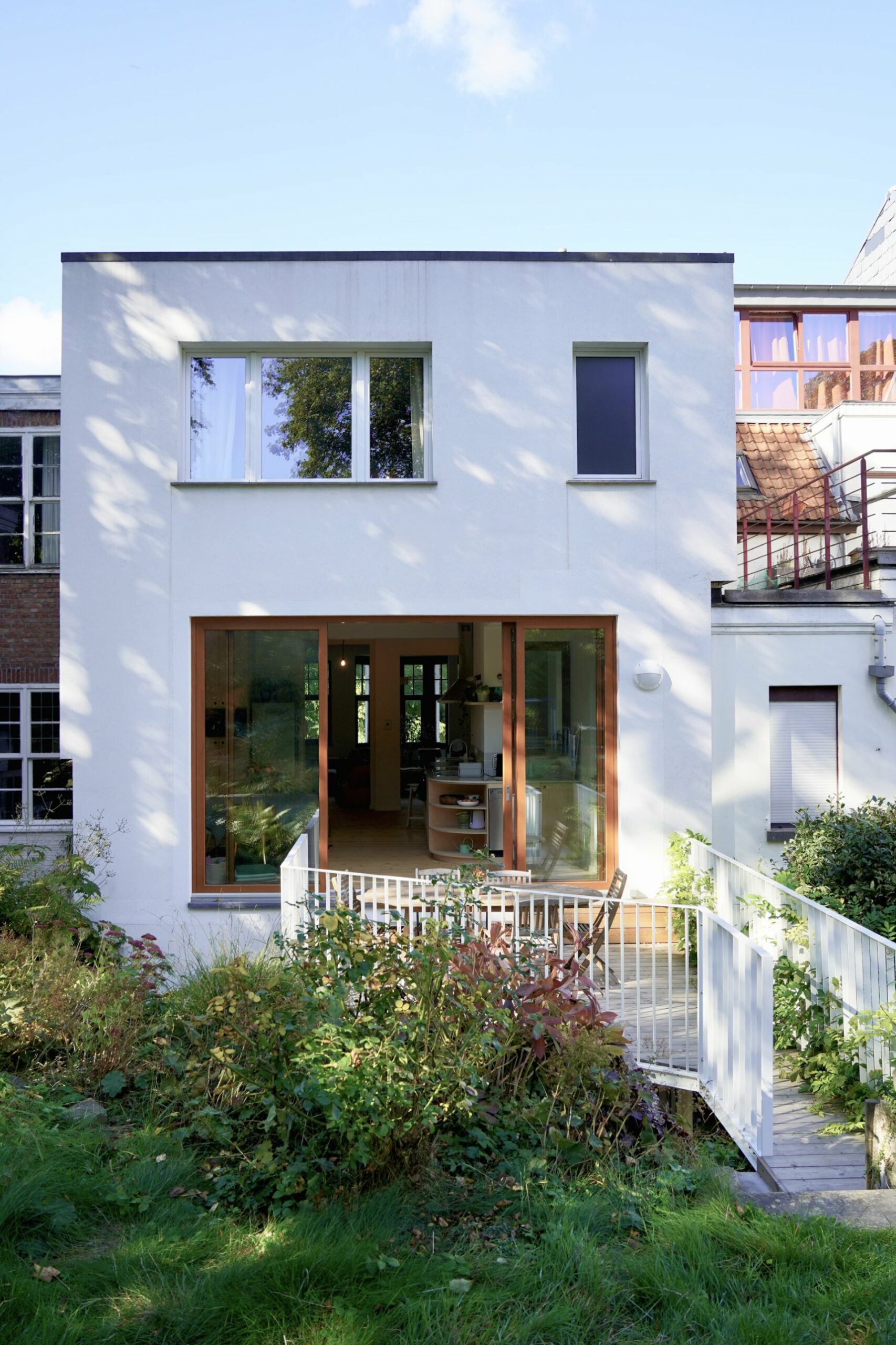 Façade arrière enduite blanche et grande baie en bois de la maison rénovée, Schaerbeek